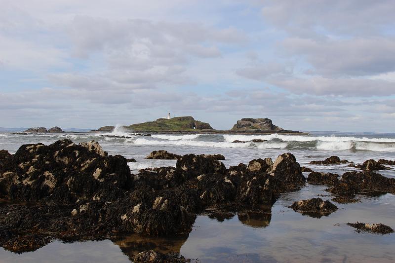 Fidra island: a long island of 2 sections, with a lighthouse on the left half, viewed from North Berwick's shore